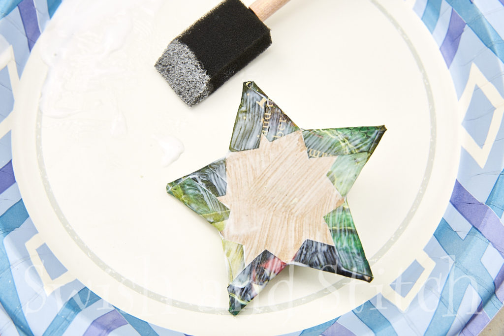 applying mod podge to the back of the papier mache star to seal