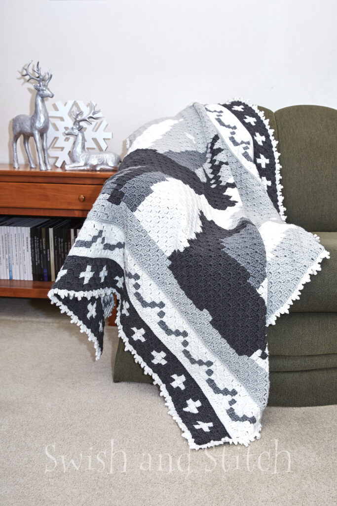 Winter Wonderland C2C Crochet Christmas Afghan draped on couch with inspiration silver deer